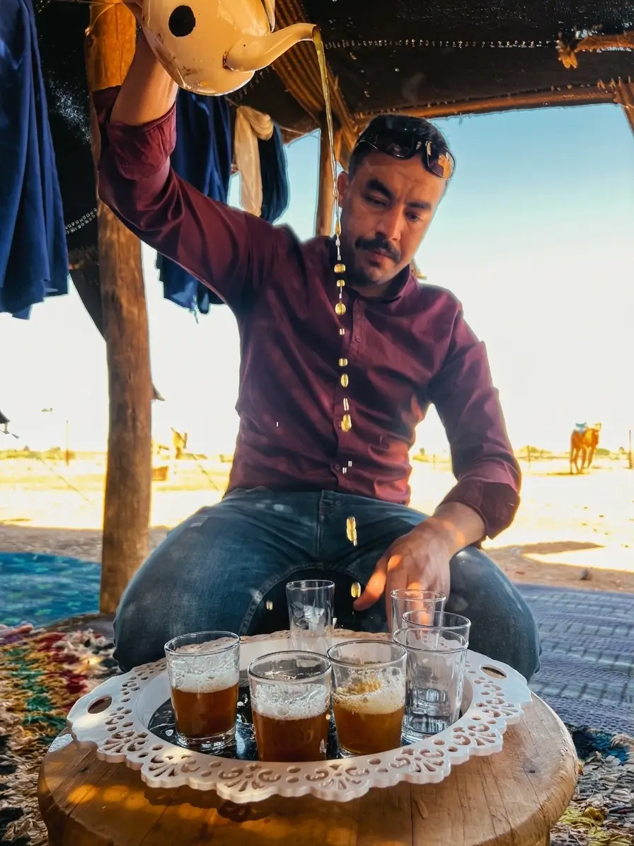 Hassan pouring Moroccan mint tea for guests at a desert camp
