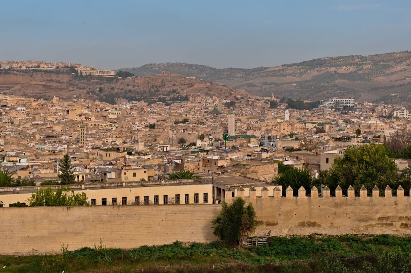 panorama over the sand-coloured rooftops of the ancient Fes medina with its ramparts and minarets