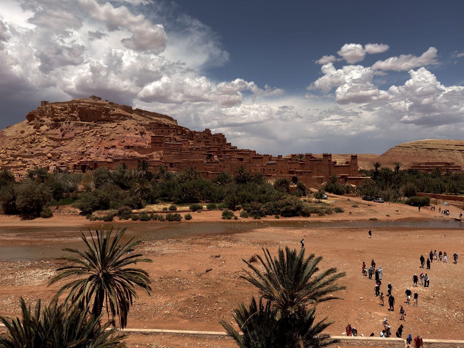 the red mud-brick ksar of Aït Benhaddou rising above palm groves near Ouarzazate under a dramatic sky